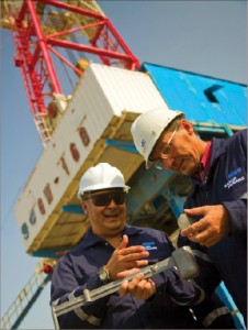 Baker Hughes drilling fluid engineers in Kazakhstan use a mud balance to check the density of a drilling mud sample. The company says that its drilling and evaluation businesses were more stressed in ’09 while its completions and production sector held up.