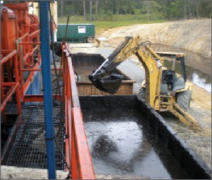 A shale shaker separates the mud from the cuttings. The mud goes back into the mud pits, located under the grate floor beneath the mud cleaning equipment. The cuttings are dropped into the cuttings box, and the backhoe scoops the cuttings off the bottom of that box. Source: Newpark Drilling Fluids, Dale Shank and Bill Mason Jr