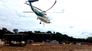 A helicopter transports a mud tank system from the base camp to the rig site. Rig equipment was broken down and transported by helicopter to the drilling sites.
